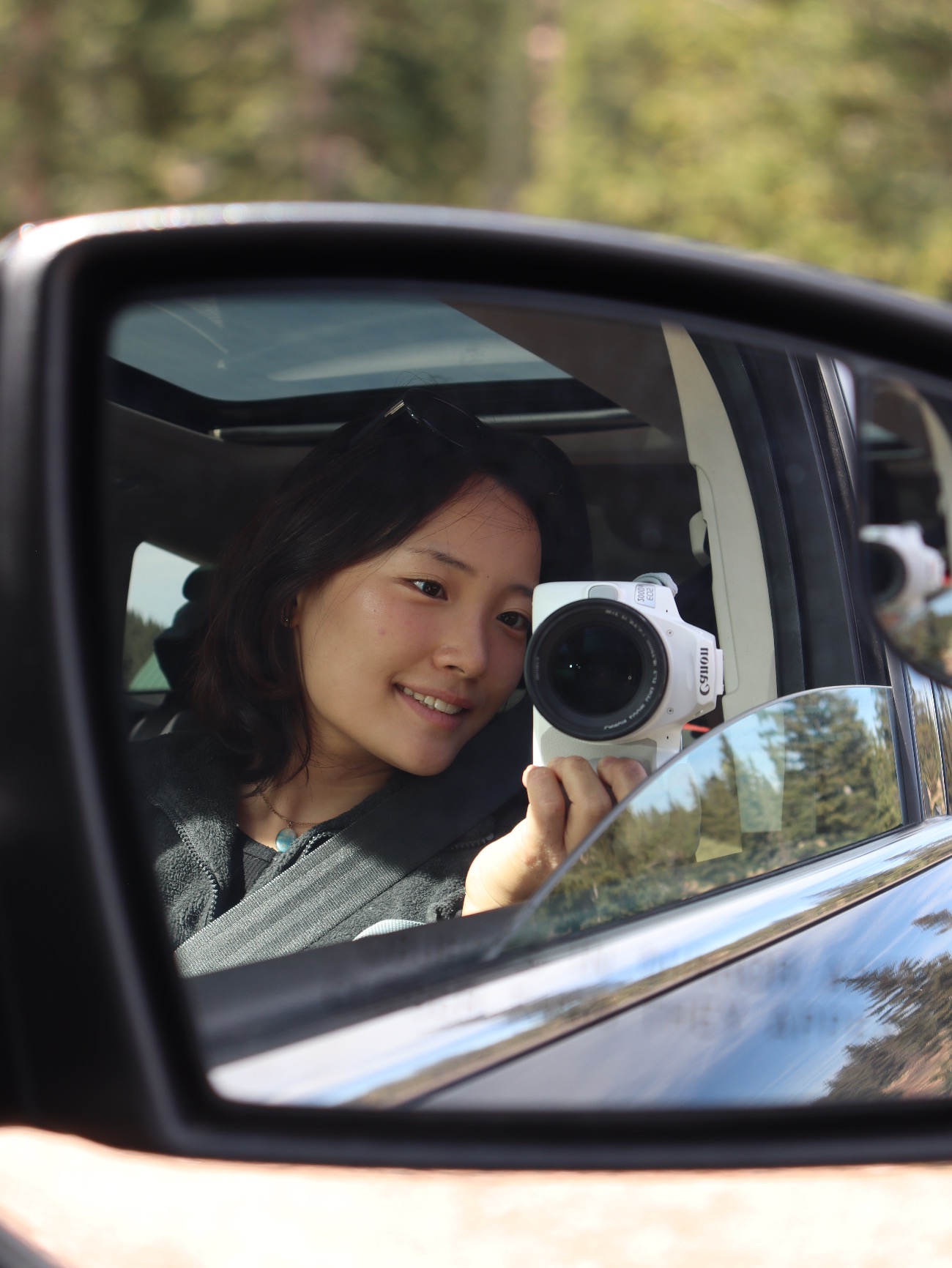 A student photographer captured in a side-mirror reflection along a Colorado road