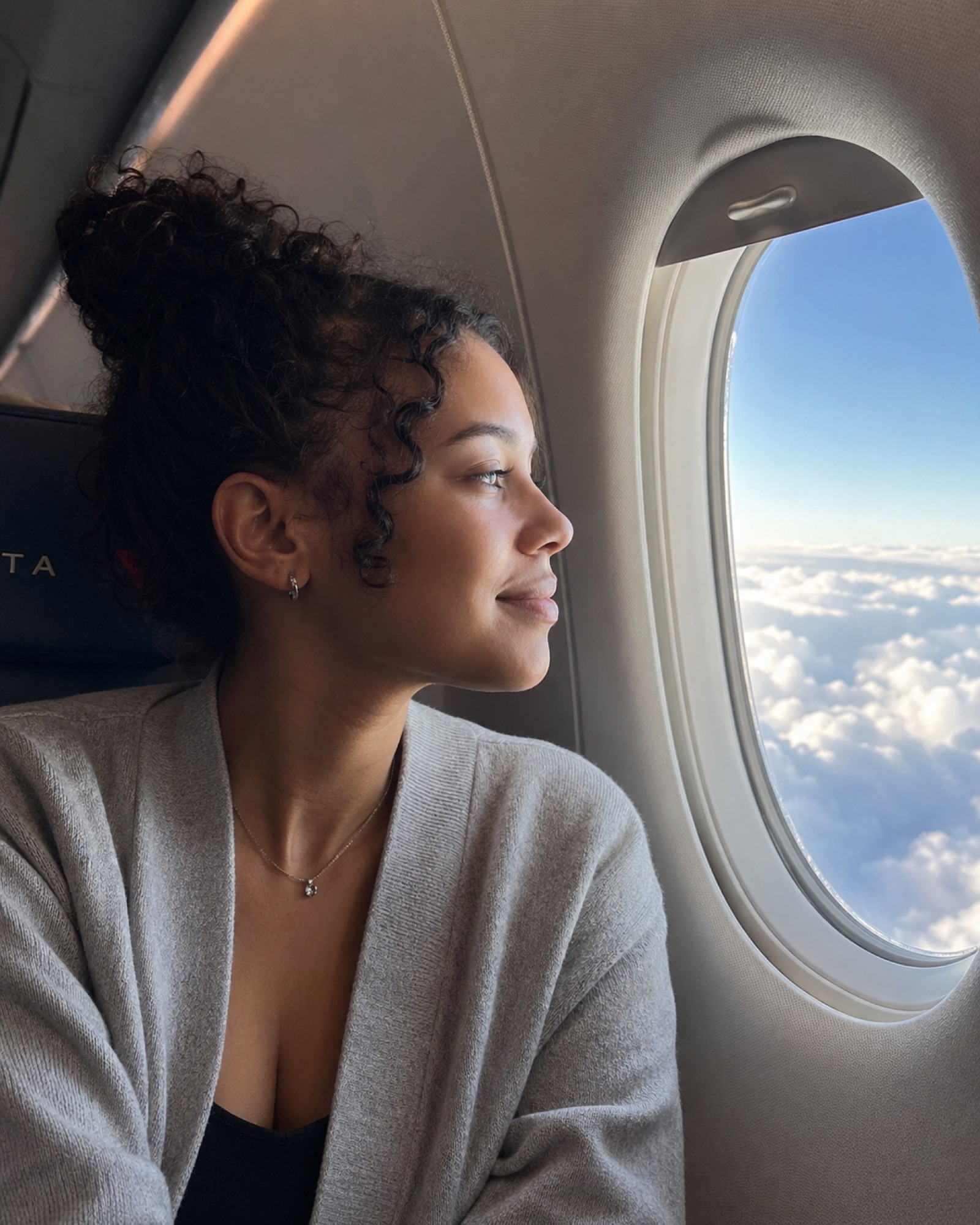 A view from an airplane window seat, wing over clouds, world below.